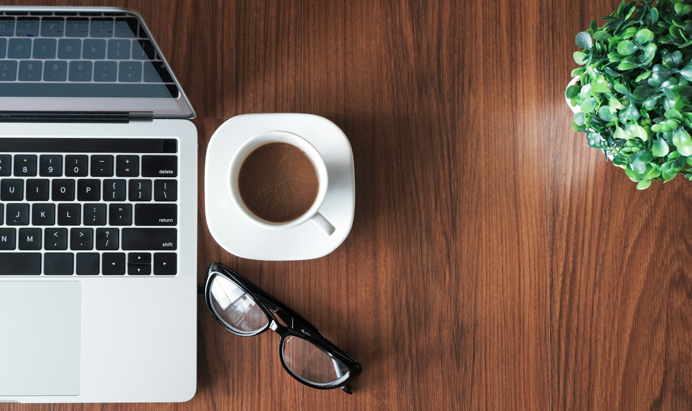 Ordinateur portable, café et plante sur un bureau en bois